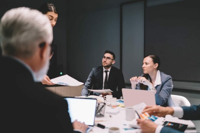 Colleagues at a conference table reviewing human oversight and escalation records for AI decisions.
