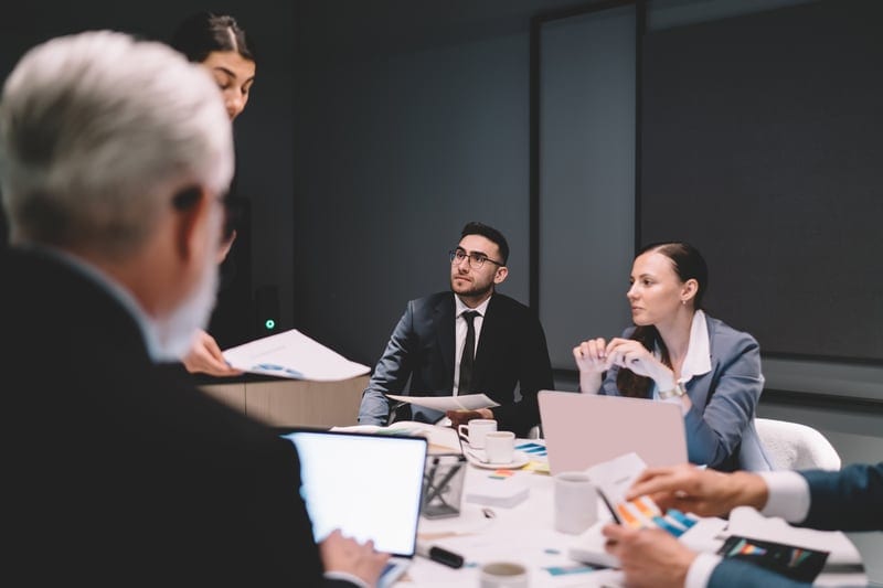 Colleagues at a conference table reviewing human oversight and escalation records for AI decisions.