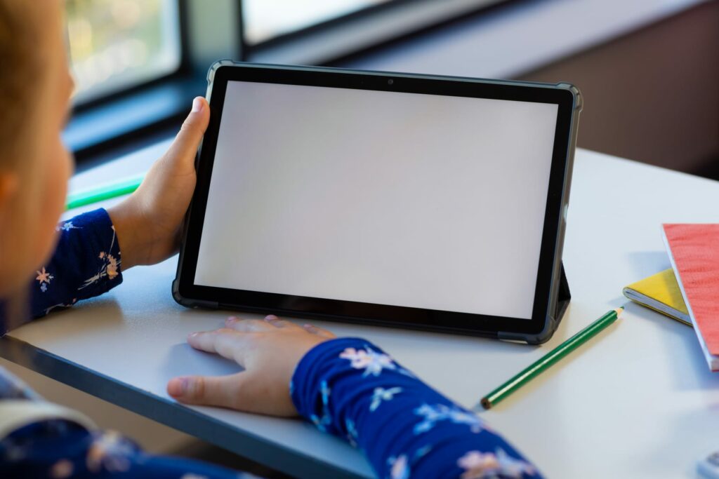 Child using a tablet in a learning setting while privacy safeguards for children's online services are reviewed.